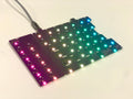 Left half of a bare Sinc PCB plugged in with a columnar gradient from pink to blue on the per-key LEDs.